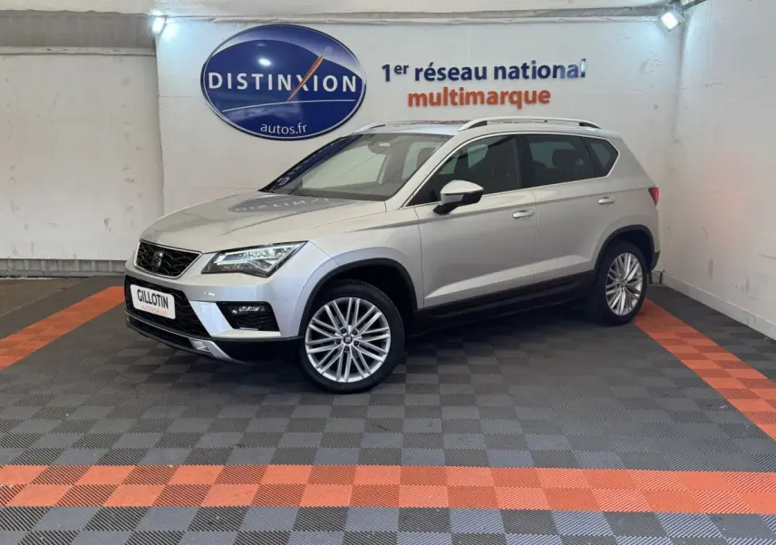 SEAT Ateca gris clair vu en 3/4 avant droit dans un showroom avec sol à damiers gris et orange.