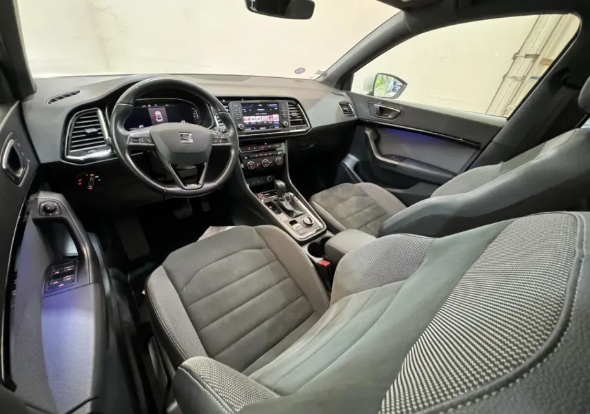 Intérieur de la SEAT Ateca vu côté conducteur, sièges gris et tableau de bord avec écran tactile central.