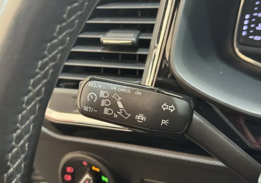 Gros plan sur la commande multifonction noire du régulateur de vitesse, tableau de bord partiel du SEAT Ateca gris clair.