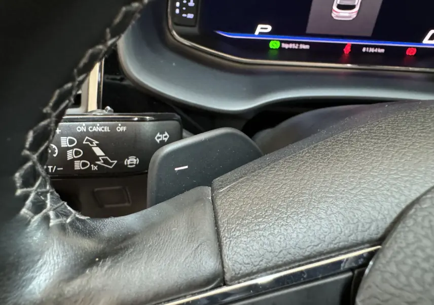 Gros plan sur le volant cuir et la palette de changement de vitesse d'une SEAT Ateca gris clair, tableau de bord numérique visible.