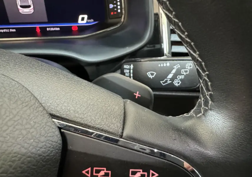 Gros plan sur le volant cuir noir d'un SEAT Ateca 2019 avec palettes de changement de vitesse et tableau de bord numérique.