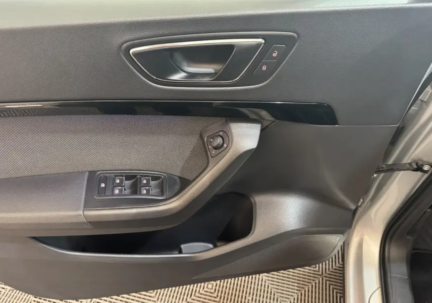 Intérieur côté conducteur de la SEAT Ateca gris clair, montrant la portière avec commandes des vitres et verrouillage.