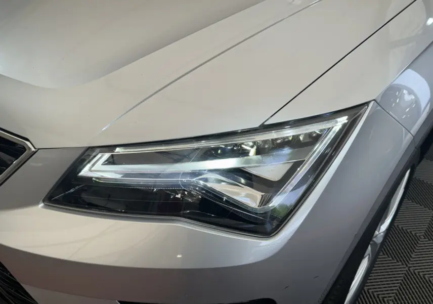 Gros plan sur le phare avant droit d’un SEAT Ateca gris clair, soulignant ses lignes modernes et précises.