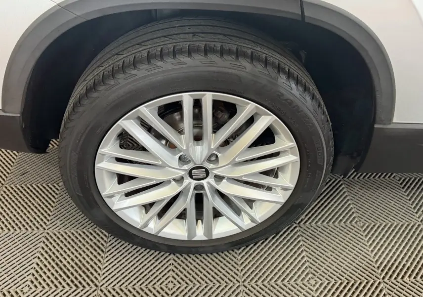 Gros plan sur la roue avant droite du SEAT Ateca gris clair, avec jante alliage à rayons fins et logo central.