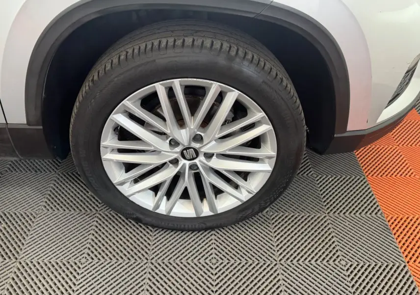 Gros plan sur la roue avant gauche d'un SEAT Ateca gris clair avec jante alliage multi-branches élégante.