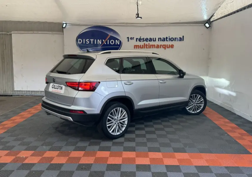 SEAT Ateca gris clair vu de trois quarts arrière droit dans un showroom avec logo Distinxion en arrière-plan.