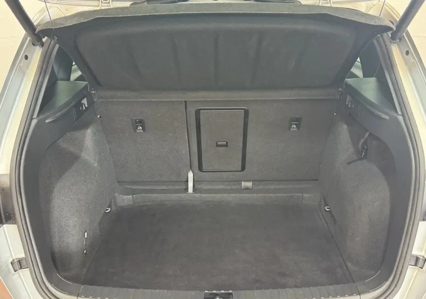 Coffre ouvert d'un SEAT Ateca gris clair, vue directe de l'espace de rangement arrière, intérieur tapissé noir.