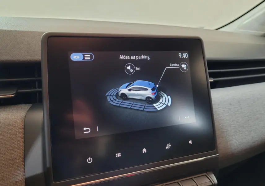 Écran tactile intérieur affichant l'aide au parking avec une Renault Clio bleue vue de dessus en illustration.