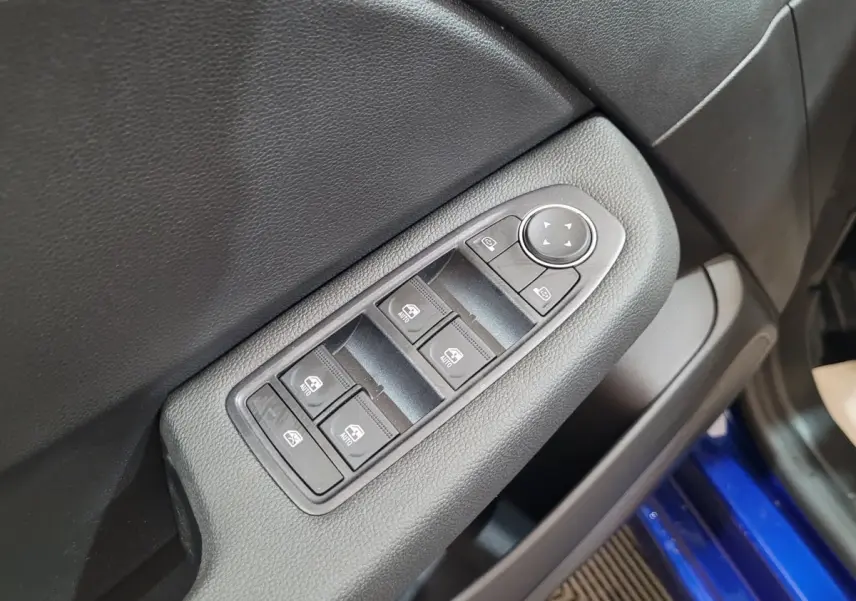 Commandes des vitres électriques sur la porte côté conducteur d'une Renault Clio bleu 2025, intérieur noir.