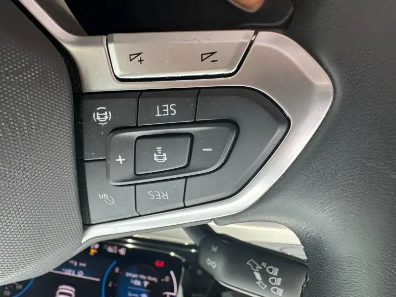 Gros plan sur les commandes au volant noir et argent de la Volkswagen Golf 1.5 eTSI 2024, avec boutons de réglage et affichage numérique partiel.