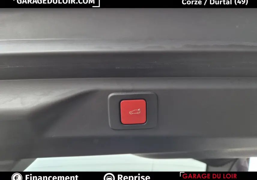 Bouton rouge d'ouverture électrique du coffre sur la partie intérieure du hayon d'un Peugeot 3008 blanc.