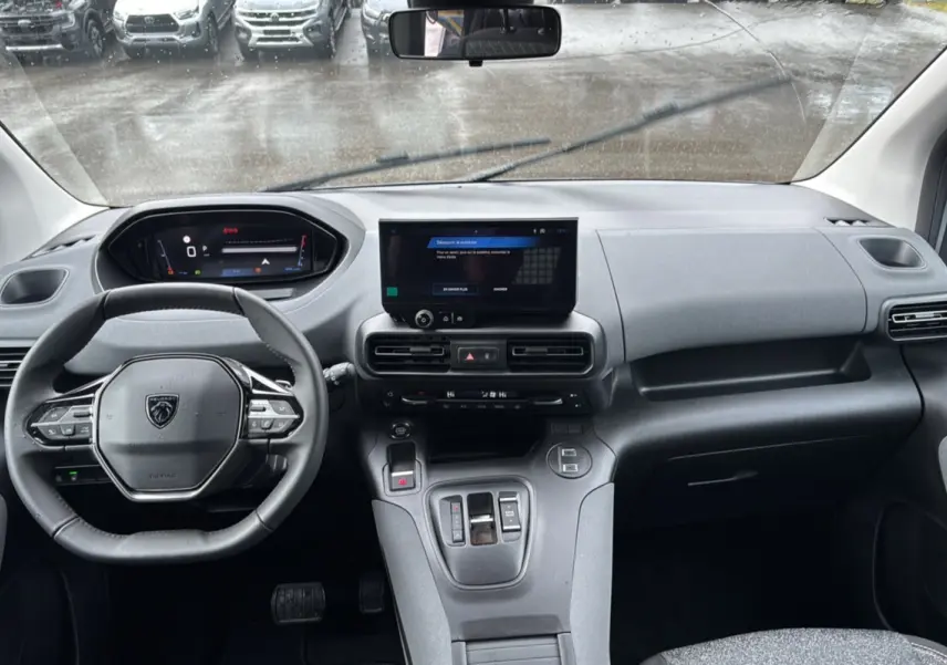 Vue intérieure avant du Peugeot Rifter 2026 gris Artense, avec tableau de bord numérique et écran tactile central.