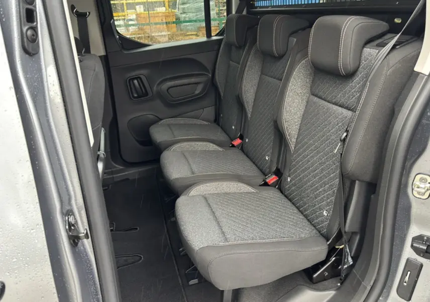 Vue intérieure côté gauche sur la banquette arrière grise tissu du Peugeot Rifter 2026 gris artense avec porte coulissante ouverte.