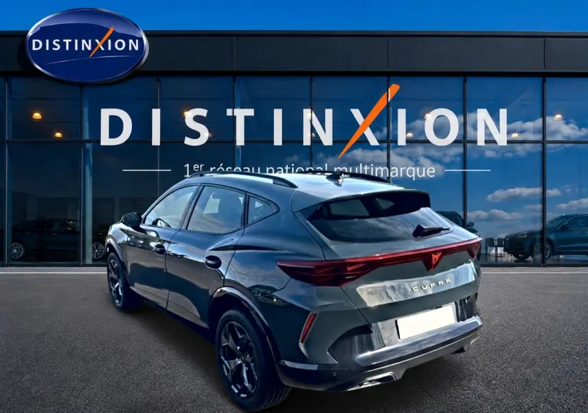 Vue 3/4 arrière droite d'un CUPRA Formentor bleu fjord avec feux arrière LED et jantes 18 pouces devant un showroom Distinxion.