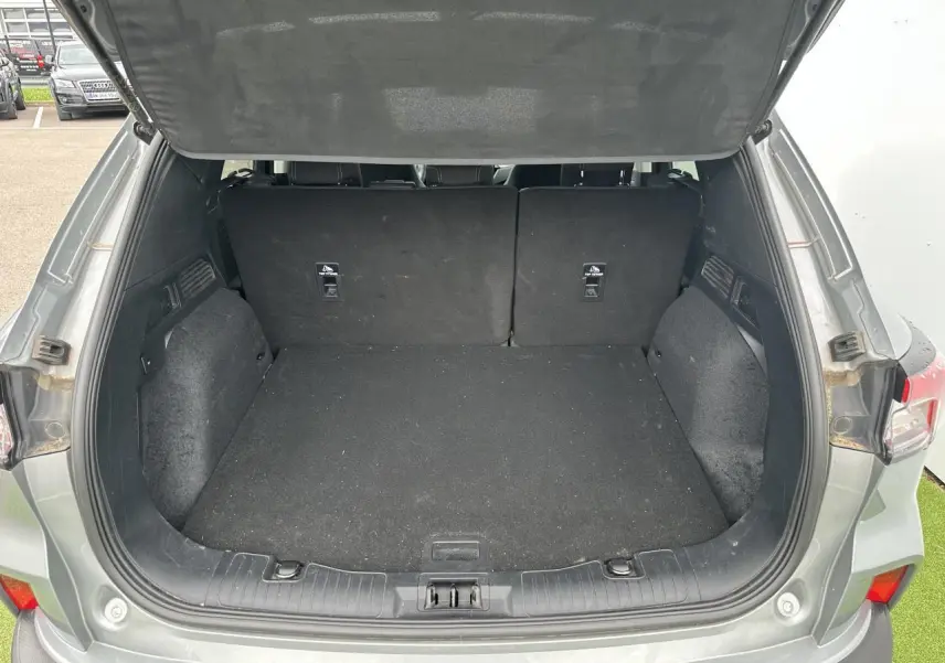 Coffre ouvert vu de l'arrière d'un Ford Kuga gris solaire, montrant un espace de chargement vide et propre.