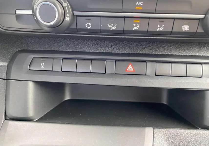 Gros plan sur la console centrale noire du Peugeot Expert Fourgon avec boutons de commande et témoin A/C allumé.