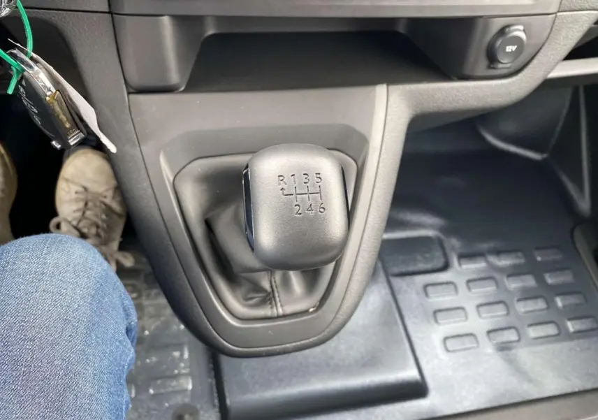 Vue rapprochée du levier de vitesses manuel noir du Peugeot Expert Fourgon blanc 2023, avec plancher caoutchouc visible.