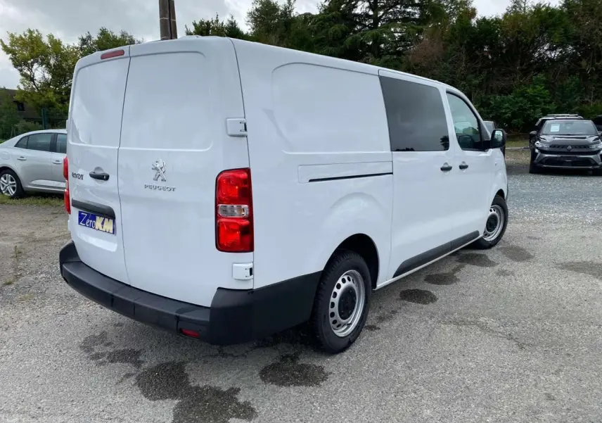 Vue 3/4 arrière droite d'un Peugeot Expert Fourgon blanc avec porte latérale coulissante et feux arrière rouges.