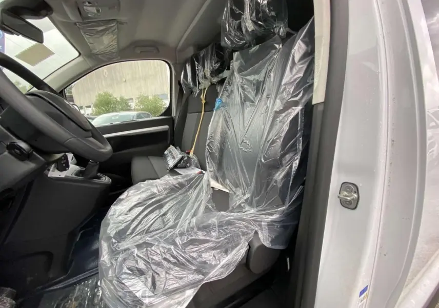 Vue intérieure côté conducteur du Peugeot Expert Fourgon blanc 2023, sièges avant protégés par film plastique.