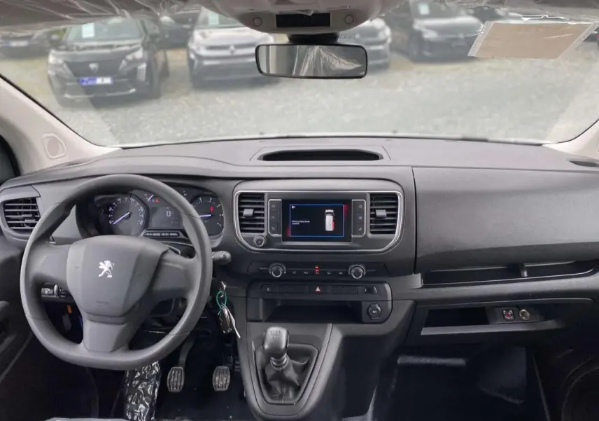 Vue intérieure du tableau de bord du Peugeot Expert Fourgon blanc 2023 avec volant, écran tactile et levier de vitesses manuel.