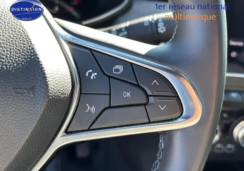 Gros plan sur les commandes gauche du volant textile enduit gris/noir de la Renault Clio V gris pizarra 2024.