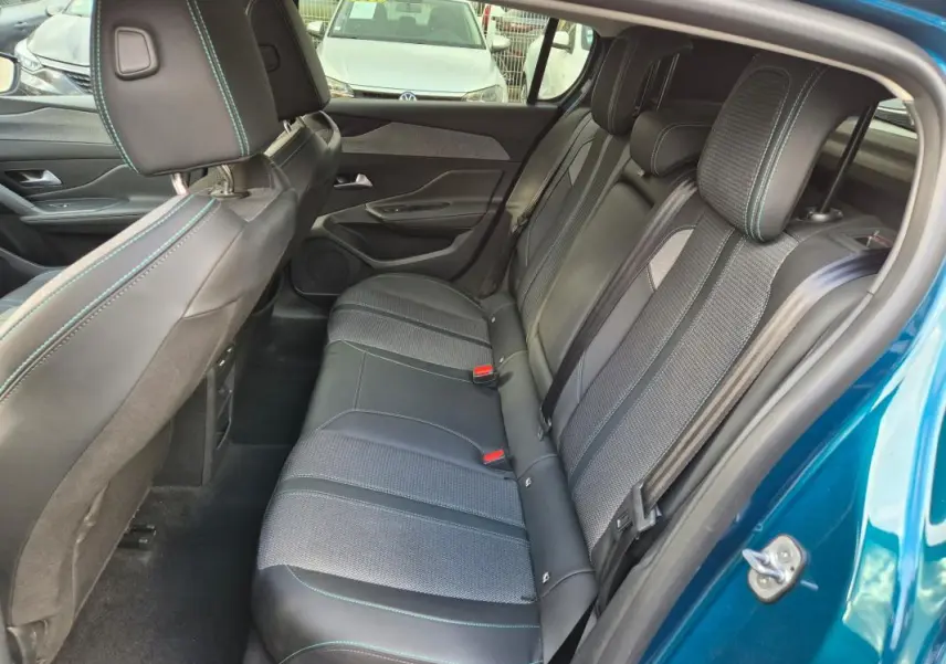 Vue intérieure côté droit des sièges arrière en tissu et cuir noir avec surpiqûres bleues d'une Peugeot 308 bleu 2024.