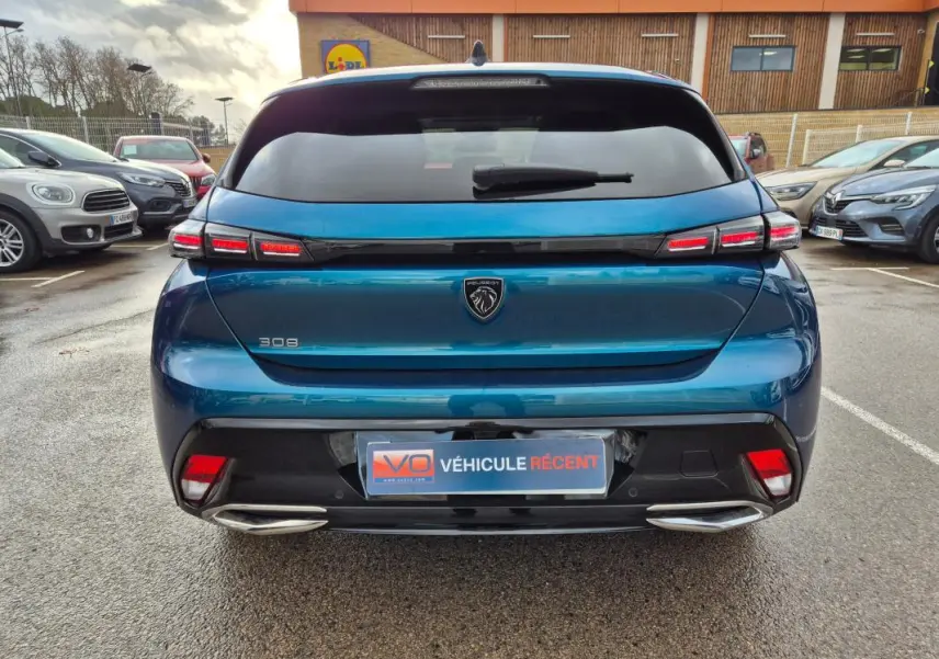 Vue arrière d'une Peugeot 308 bleu 2024 avec feux LED distinctifs et double sortie d'échappement chromée.
