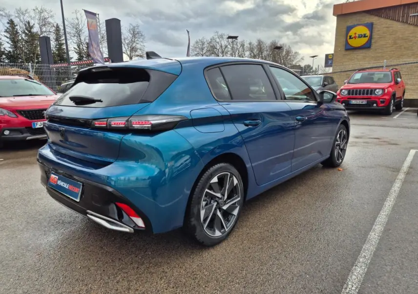 Vue 3/4 arrière droite d'une Peugeot 308 bleu métallisé 2024 avec jantes alliage et feux arrière LED distinctifs.