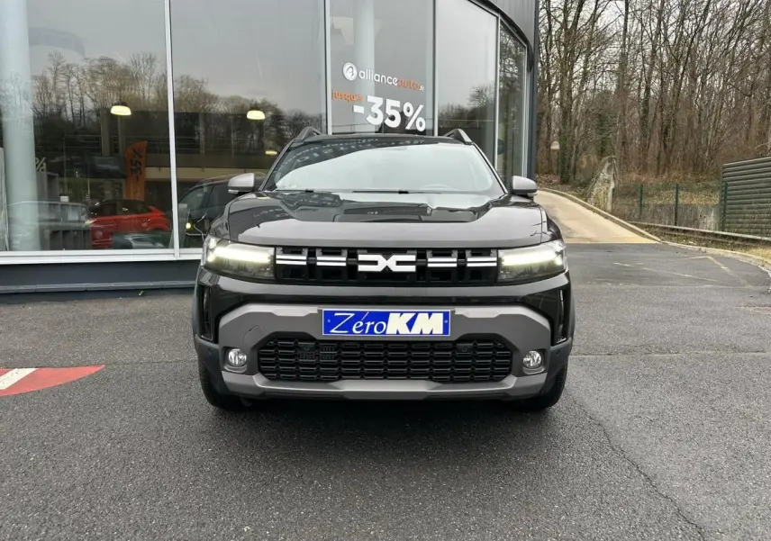 Vue frontale du Dacia Duster noir métallisé 2025 avec signature lumineuse LED et plaque Zéro KM visible.