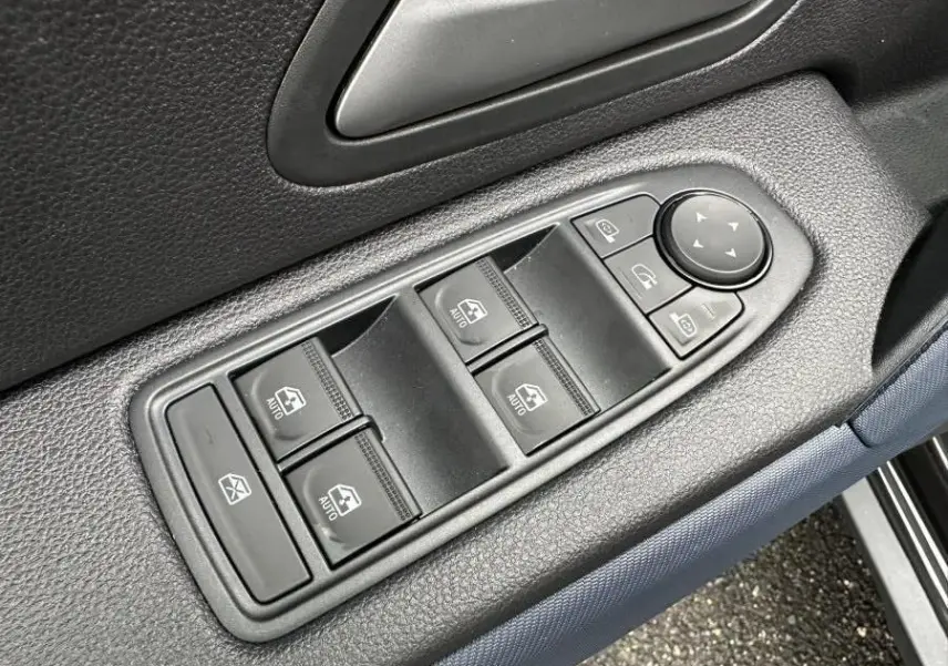 Gros plan sur les commandes des vitres et rétroviseurs côté conducteur du Dacia Duster noir 2025.