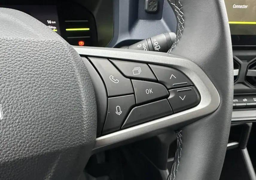 Gros plan sur les commandes au volant côté droit du Dacia Duster 2025 noir, avec tableau de bord partiellement visible.