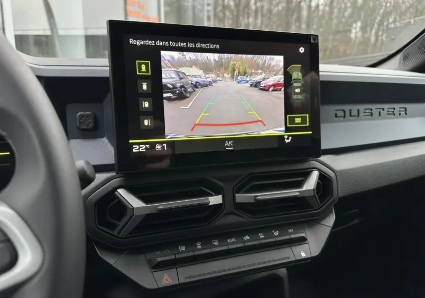 Vue intérieure du tableau de bord du Dacia Duster 2025 noir, avec écran de caméra de recul et aérateurs hexagonaux.