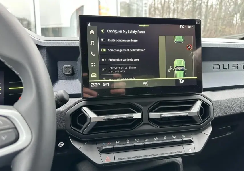 Vue intérieure du tableau de bord du Dacia Duster noir 2025, avec écran tactile central affichant les aides à la conduite.