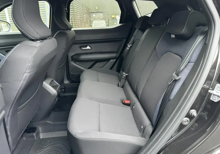 Vue côté droit de la banquette arrière noire du Dacia Duster 2025 avec ceinture et appuie-têtes intégrés.