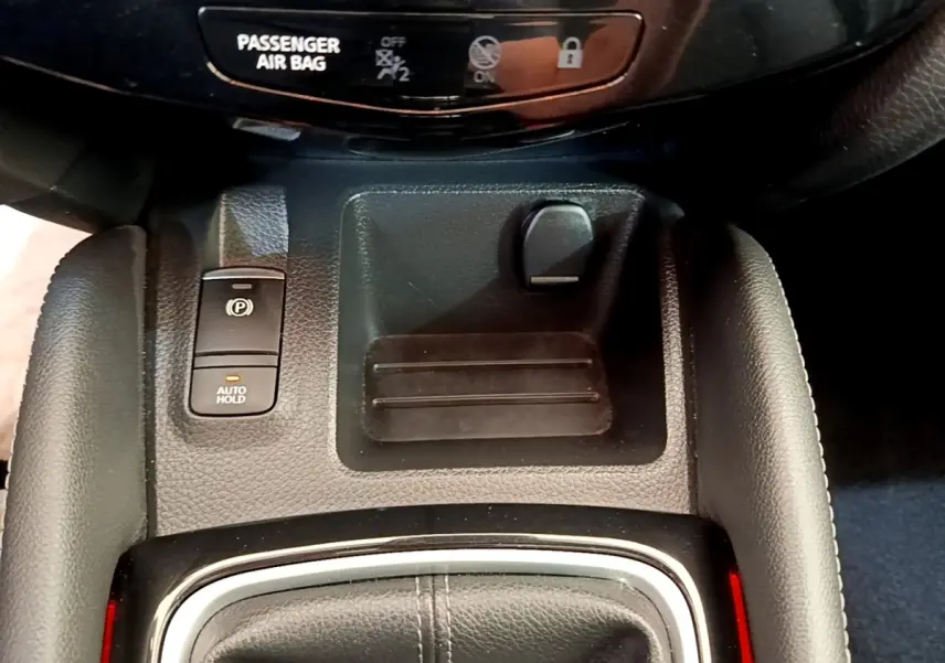 Gros plan sur la console centrale du Nissan Qashqai blanc, avec frein à main électrique et bouton Auto Hold.