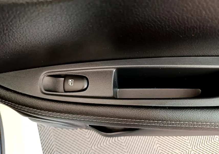 Détail de la commande de lève-vitre sur la porte intérieure côté conducteur d’un Nissan Qashqai blanc 2019.