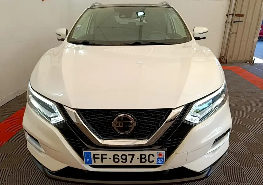 Vue avant d'un Nissan Qashqai blanc avec phares LED allumés et calandre noire chromée.