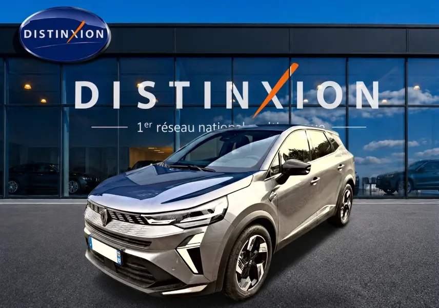 Renault Symbioz gris cassiopée en 3/4 avant droit, avec calandre distinctive et jantes modernes devant showroom Distinxion.