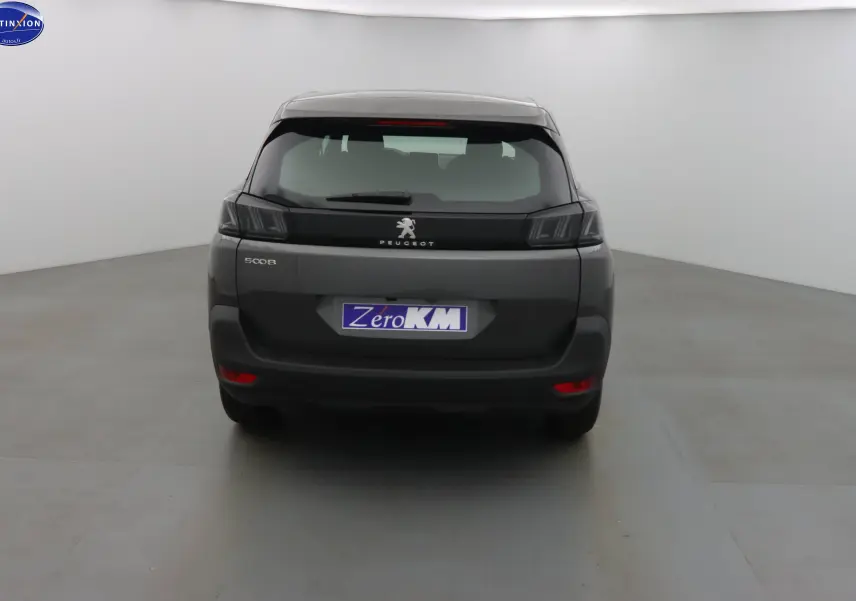 Vue arrière d'un Peugeot 5008 gris platinium métal 2023 avec feux arrière sombres et plaque Zero KM.