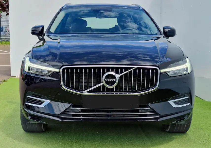 Vue frontale du Volvo XC60 noir 2021 avec calandre chromée et phares LED allumés.