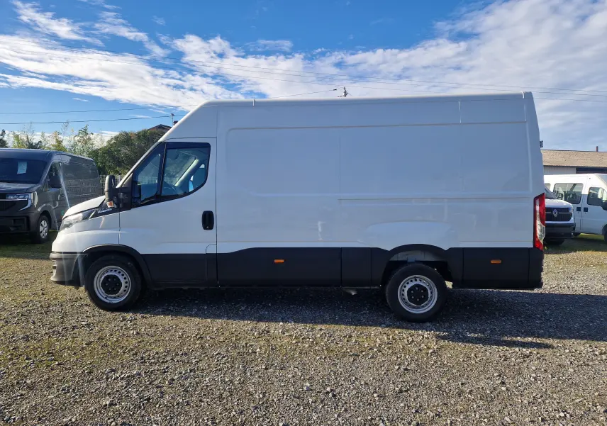 Fourgon Iveco Daily blanc vu de profil côté gauche, avec bas de caisse noir et marchepied arrière visible.