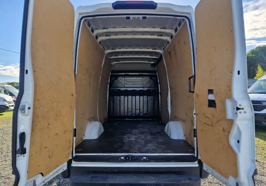 Vue arrière ouverte du fourgon Iveco Daily blanc 2022, montrant l'espace de chargement avec parois en bois et marchepied noir.