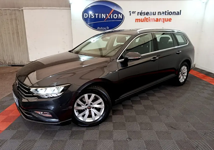 Volkswagen Passat break gris foncé vue 3/4 avant droit dans un showroom intérieur avec logo Distinxion en arrière-plan