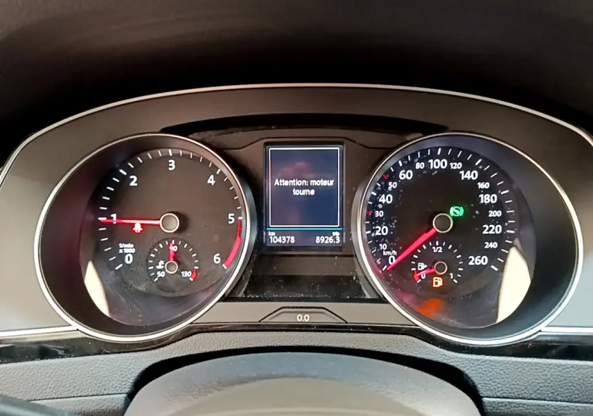 Tableau de bord de Volkswagen Passat gris foncé, affichage digital central avec message moteur et compteurs analogiques.