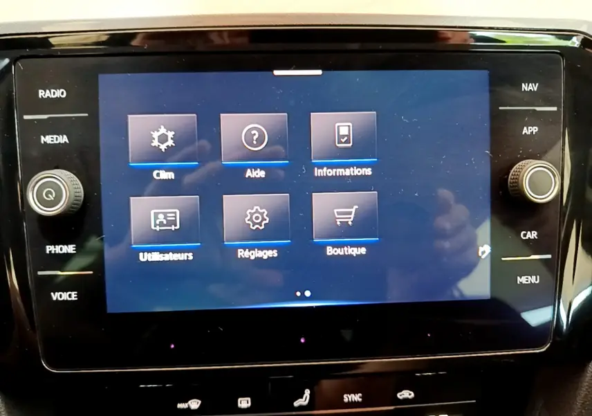 Écran tactile central de la Volkswagen Passat 2021 affichant le menu principal avec options clim, aide et réglages.