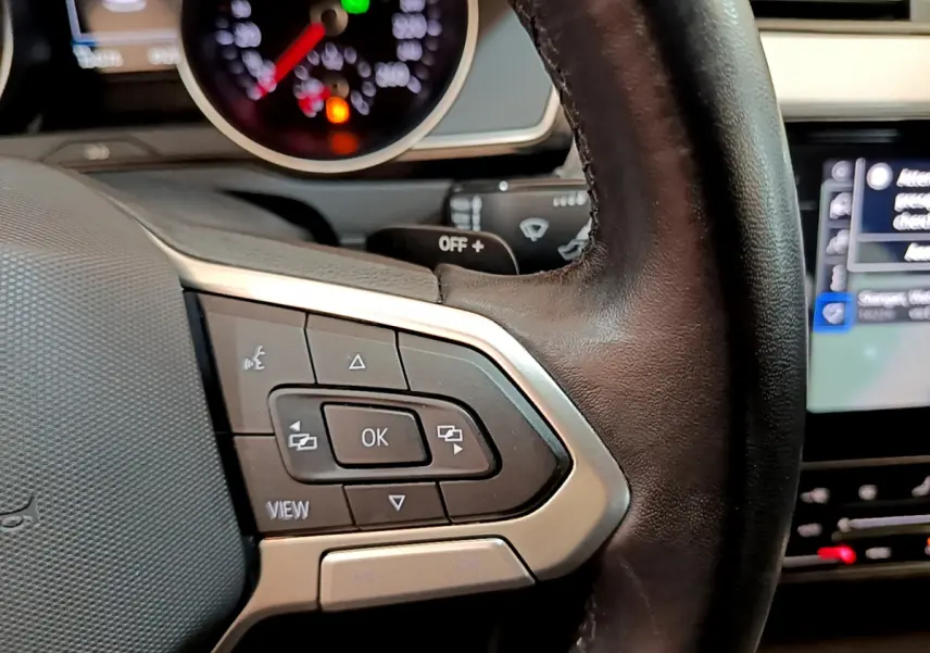 Gros plan sur les commandes multifonctions du volant cuir noir de la Volkswagen Passat gris foncé 2021.