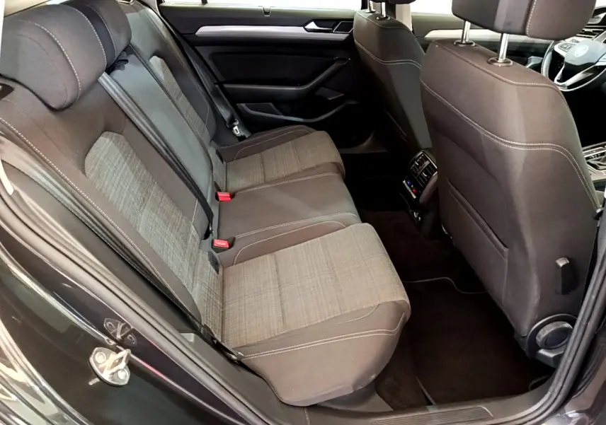 Vue intérieure arrière côté gauche d'une Volkswagen Passat gris foncé, sièges tissu bicolore avec coutures contrastées.