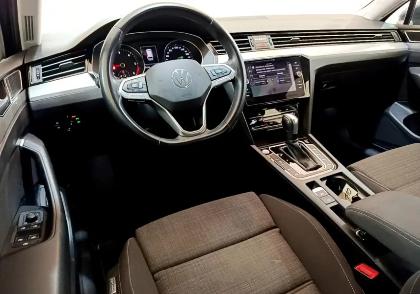Vue intérieure avant droite du tableau de bord et volant cuir de la Volkswagen Passat 2.0 TDI gris foncé avec écran tactile central.