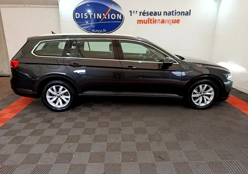Profil côté droit d'une Volkswagen Passat break gris foncé 2021, stationnée en intérieur sur sol damier.