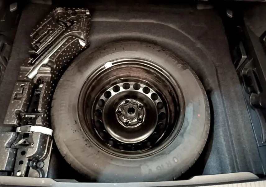 Vue plongeante sur la roue de secours acier noire dans le coffre gris foncé d'une Volkswagen Passat 2021.